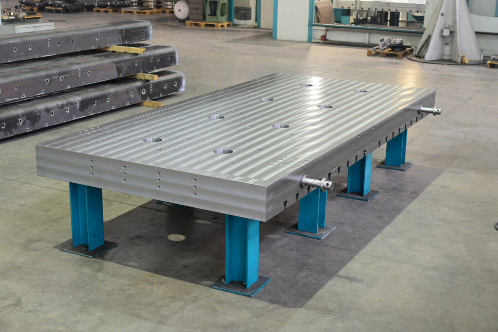Large machined steel base plate on blue industrial supports