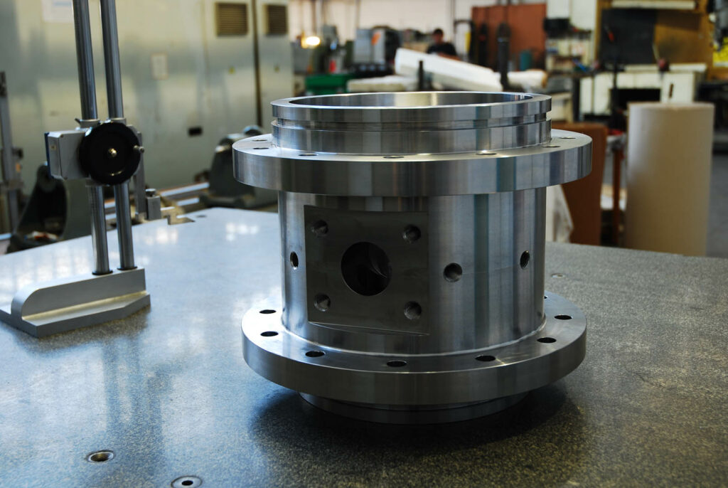 Precision-machined cylindrical housing with flanges and drilled ports