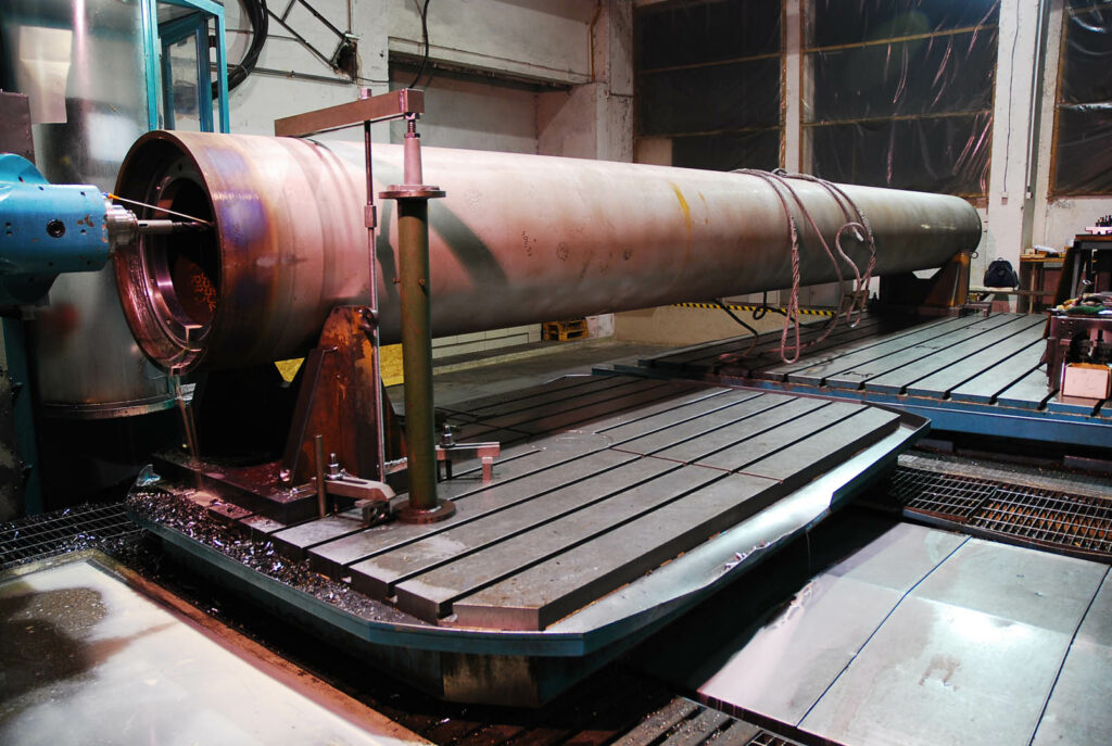 Large cylindrical rotor undergoing CNC machining for pulp and paper production equipment