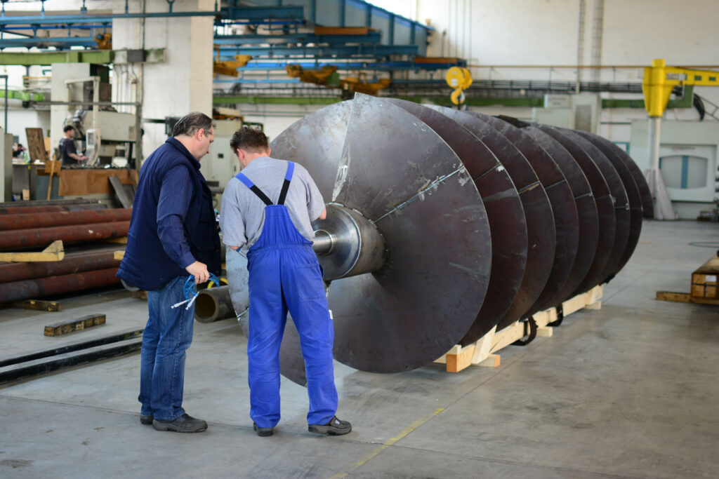 Two workers inspecting a large industrial helix rotor for the pulp and paper industry
